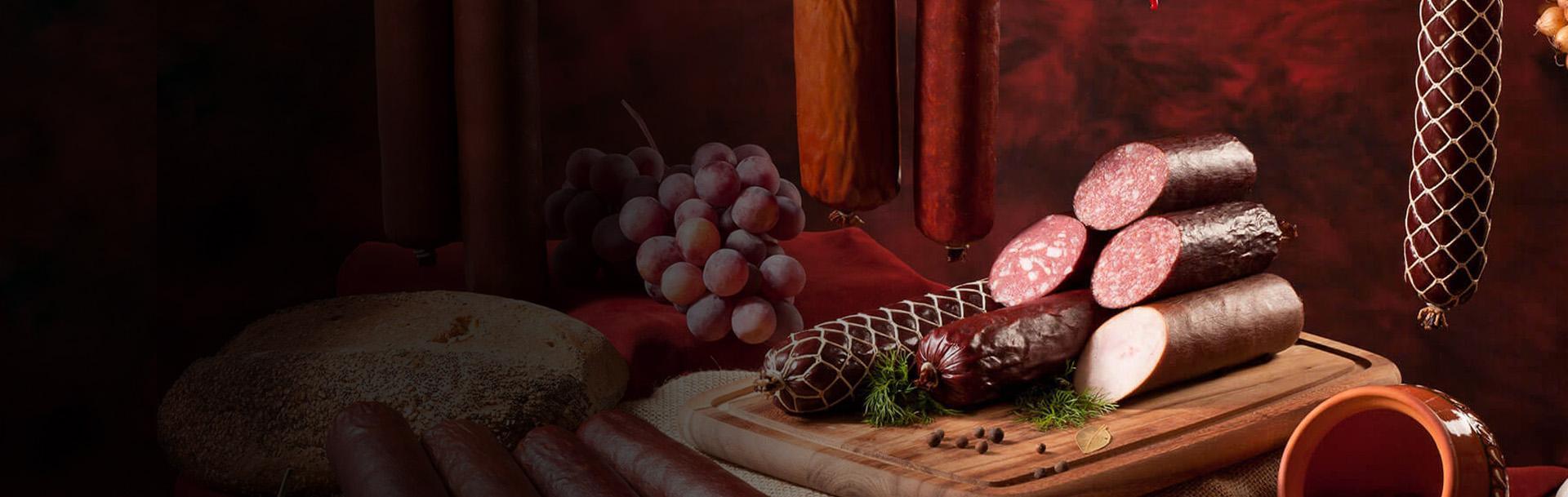 wiszące kiełbasy kiełbasy leżące na desce chleb i winogrona